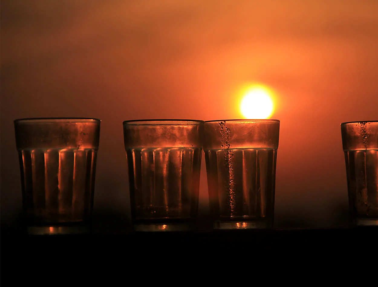 Glasses of tea lined up against a sunrise